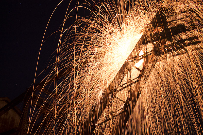 Photograph of welding sparks at night.