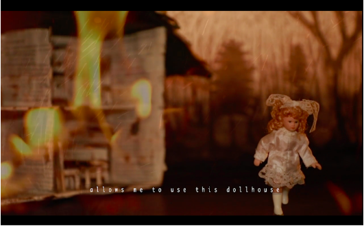 The interior of house made out of paper from a book. The inside of the house is on fire. The background of the image is blurry with outlines of tress.In the right foreground, there is a porcelain doll in a white dress that appears to be walking. There is text at the bottom of the image that reads 'allows me to use this dollhouse.'