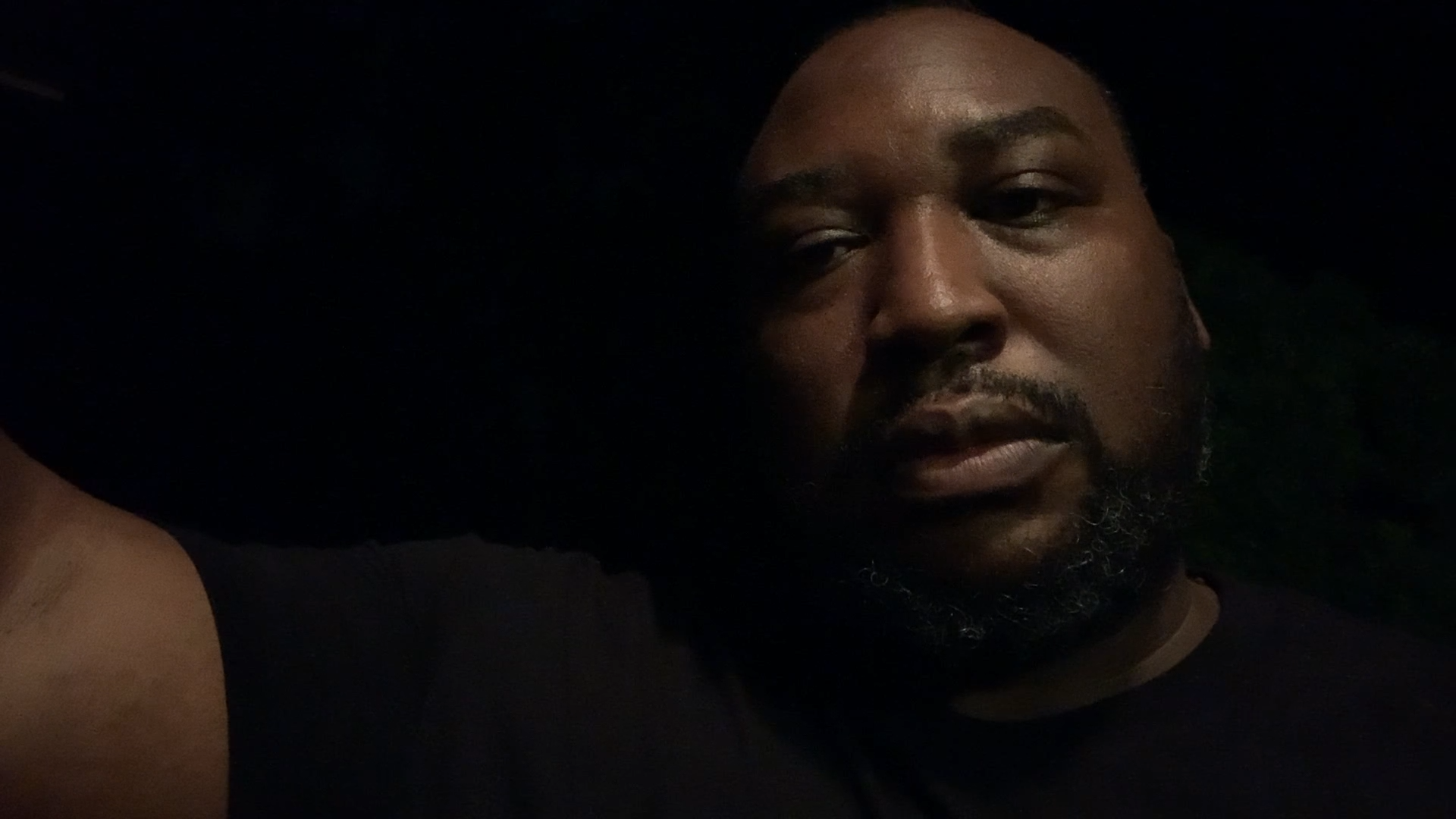 An African American man with a forlorn expression in front of a black background.